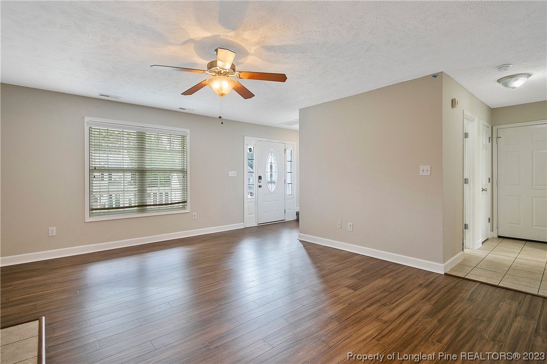 89 Rockingham Street Spring Lake, NC 28390 - Photo 8 of 41 an empty room with wooden floor chandelier fan and windows