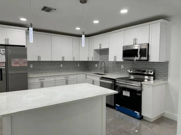 a kitchen with stainless steel appliances a stove a sink a microwave and cabinets