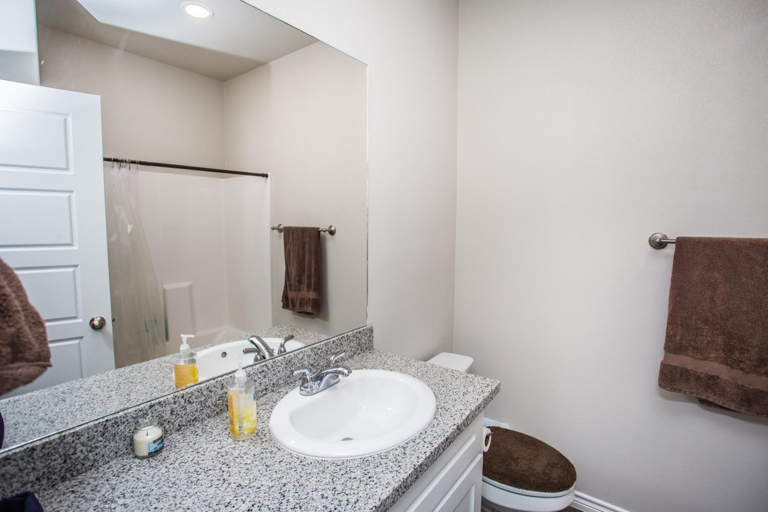 7004 10th Street Lubbock, TX 79416 - Photo 19 of 32 a bathroom with a granite countertop sink and a mirror