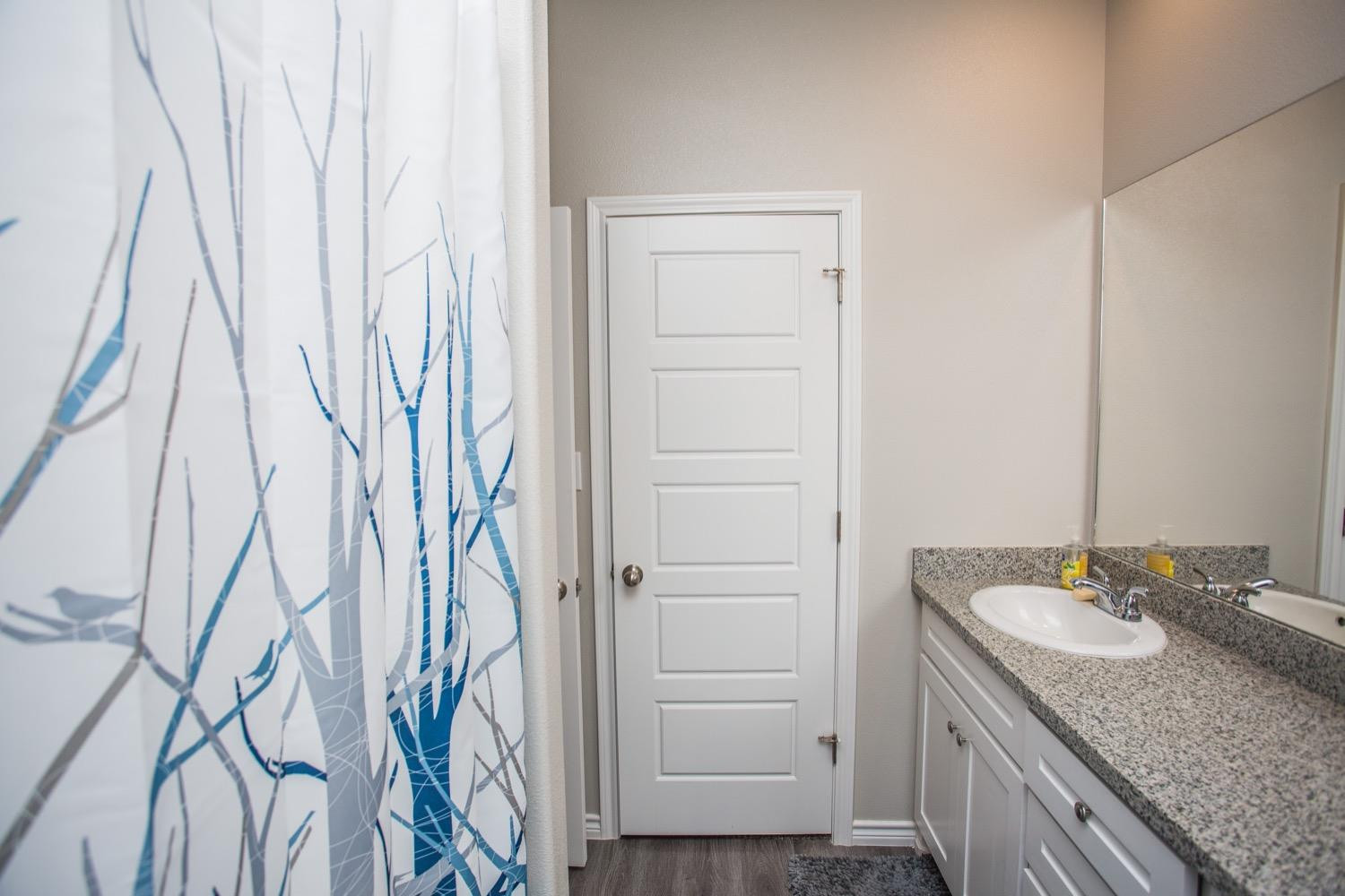 7004 10th Street Lubbock, TX 79416 - Photo 26 of 32 a bathroom with a granite countertop sink and a mirror