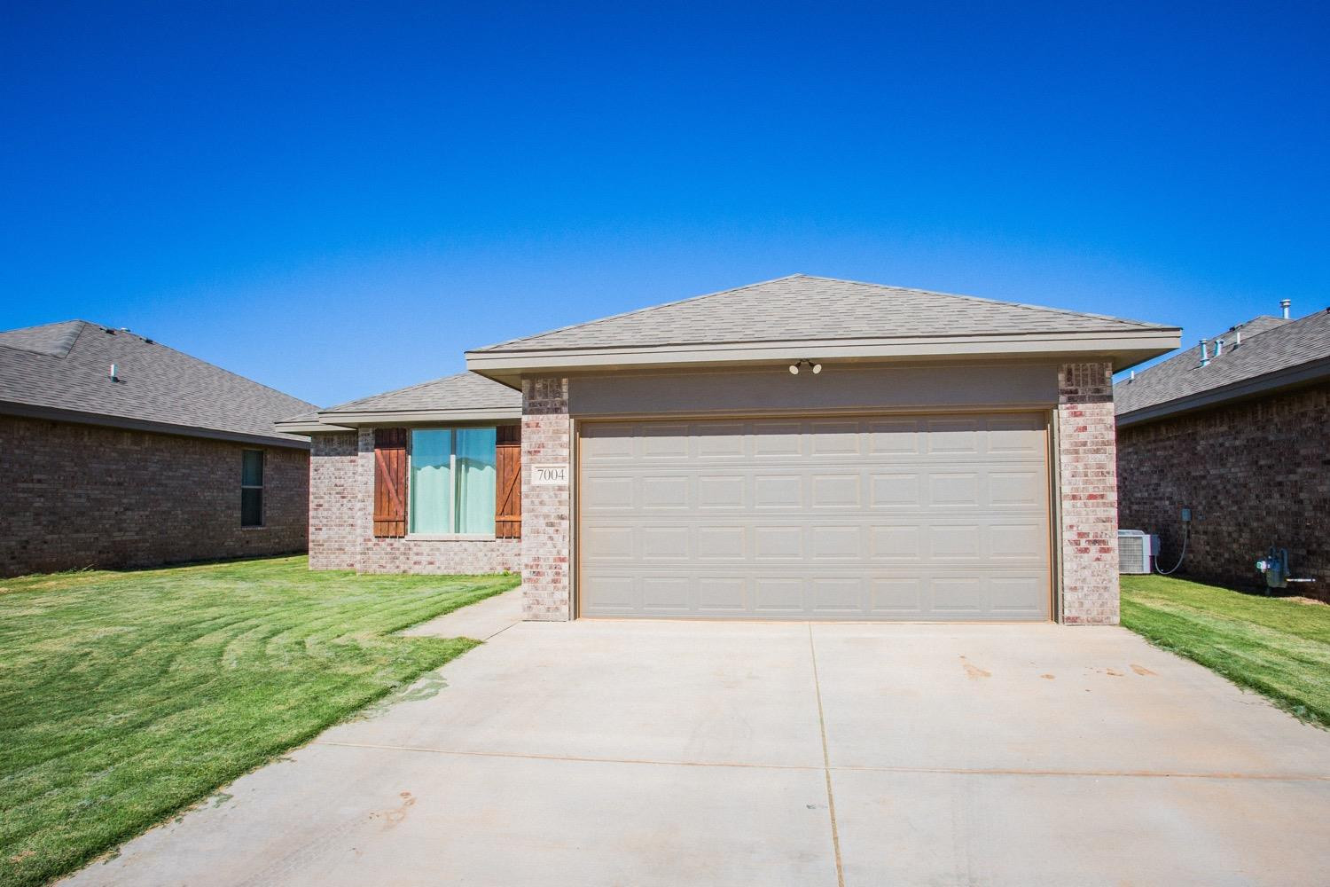 7004 10th Street Lubbock, TX 79416 - Photo 3 of 32 a front view of a house with a yard and garage
