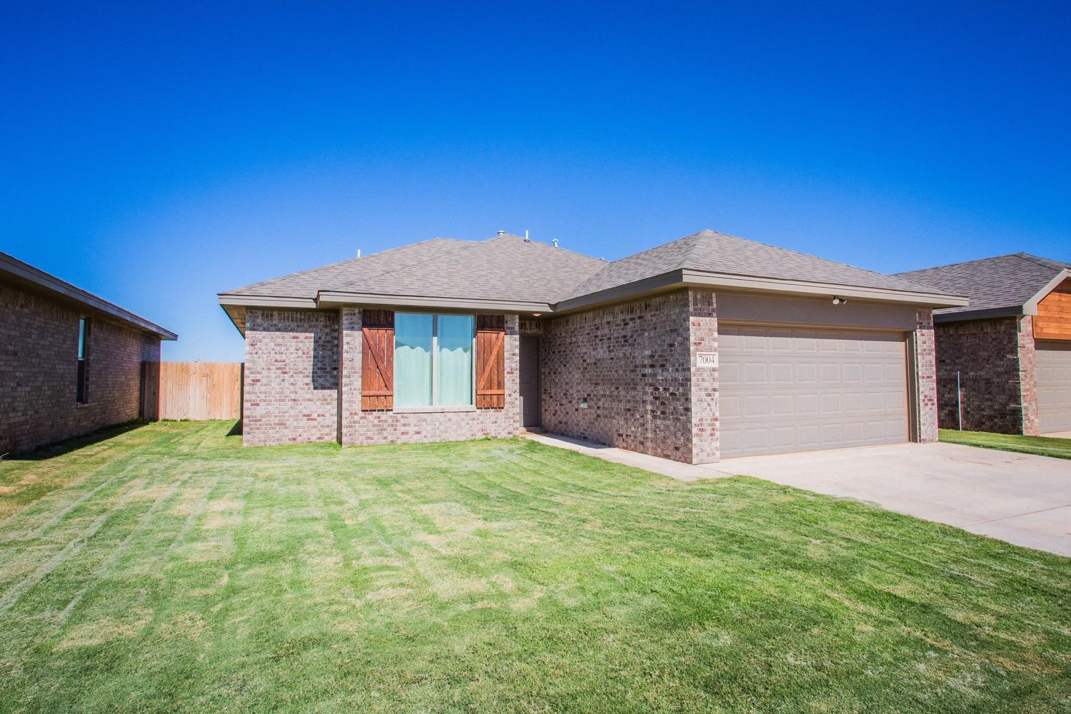 7004 10th Street Lubbock, TX 79416 - Photo 4 of 32 a front view of a house with a yard garage and a tree