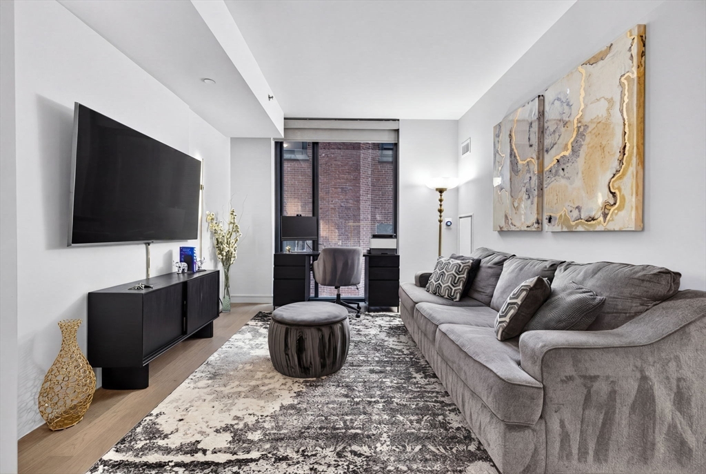 55 Lagrange Street, Unit 409 Boston, MA 02111 - Photo 2 of 29 a living room with furniture and a flat screen tv