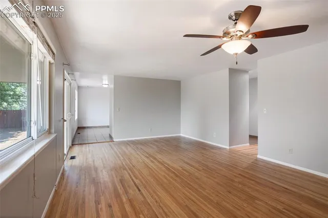 a view of an empty room with wooden floor and a window