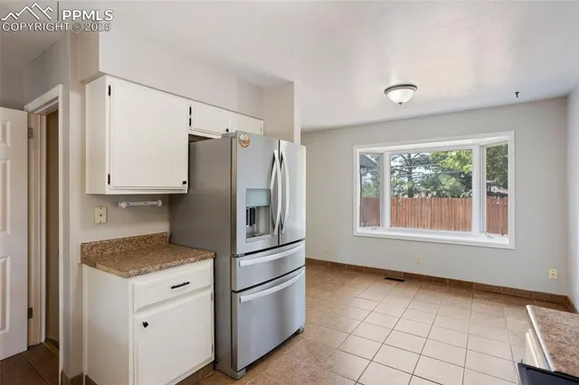 a kitchen with a refrigerator and white cabinets