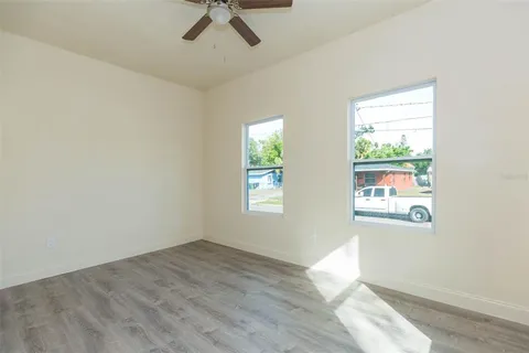 a view of empty room with wooden floor and fan