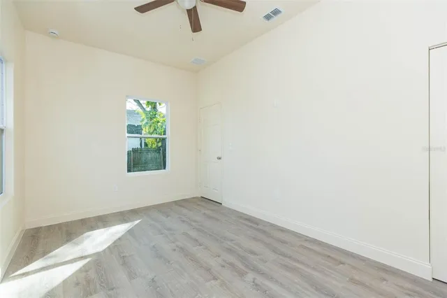 an empty room with a window and a ceiling fan