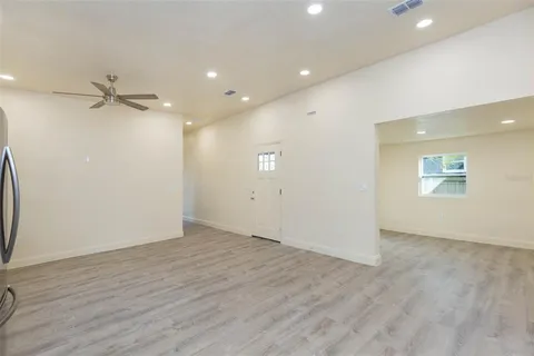 an empty room with wooden floor fan and windows