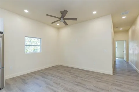 an empty room with wooden floor closet and windows