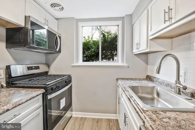 a kitchen with granite countertop a stove a sink and a microwave