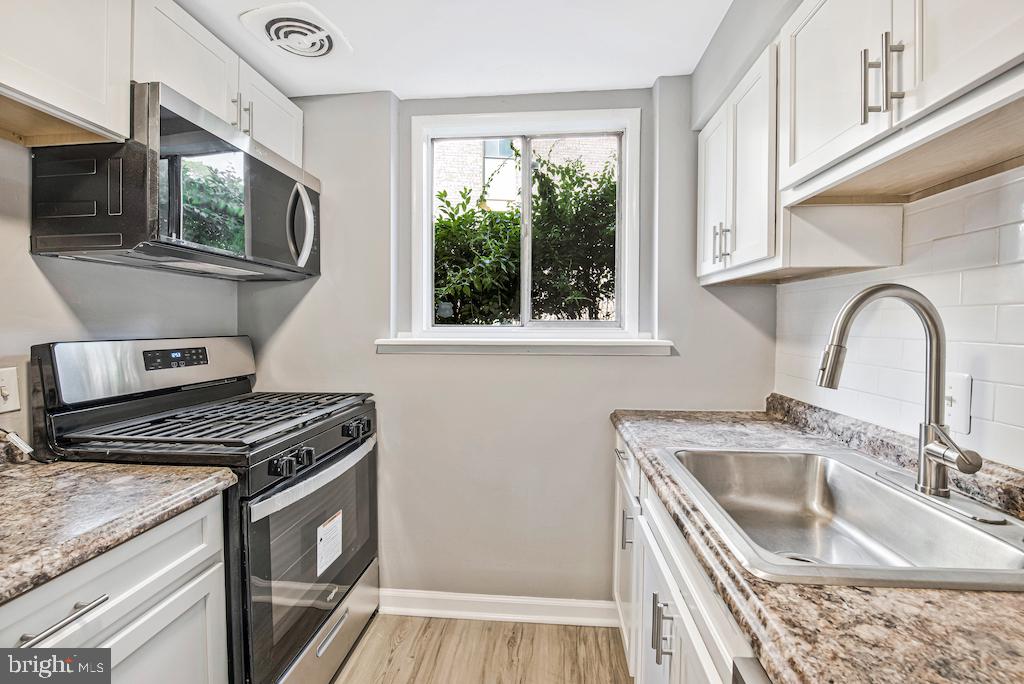 7129 Donnell Place, Unit A District Heights, MD 20747 - Photo 12 of 25 a kitchen with granite countertop a stove a sink and a microwave