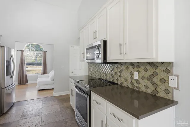 an empty room with chandelier fan and windows