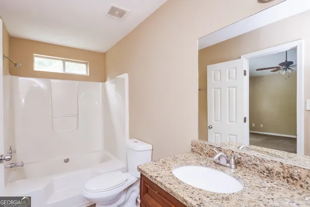 a bathroom with a granite countertop sink toilet and shower