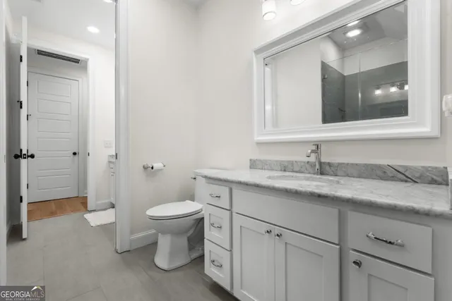 a bathroom with a granite countertop toilet sink and mirror