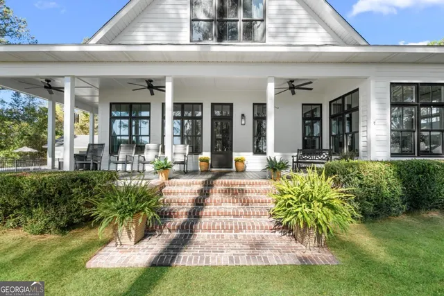 a view of a patio with table and chairs potted plants and large tree