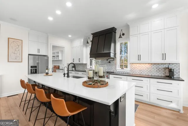 a kitchen with stainless steel appliances kitchen island granite countertop a table chairs sink and cabinets