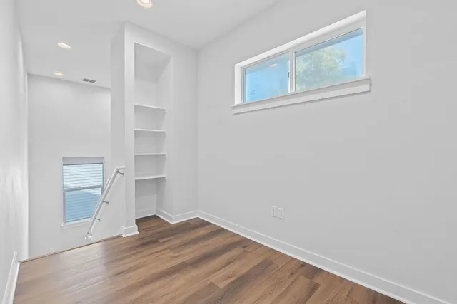 an empty room with wooden floor and windows