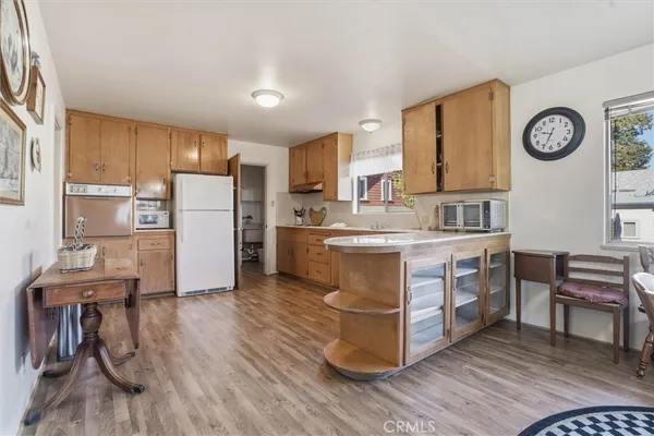 a kitchen with kitchen island a stove a refrigerator and a dining table with wooden floor