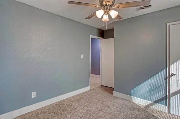 an empty room with a chandelier fan and windows
