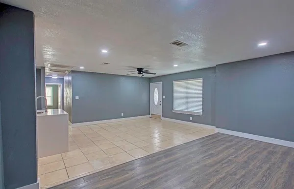 a view of an empty room with wooden floor and windows