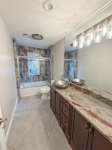 a spacious bathroom with a granite countertop sink a large mirror and a bathtub