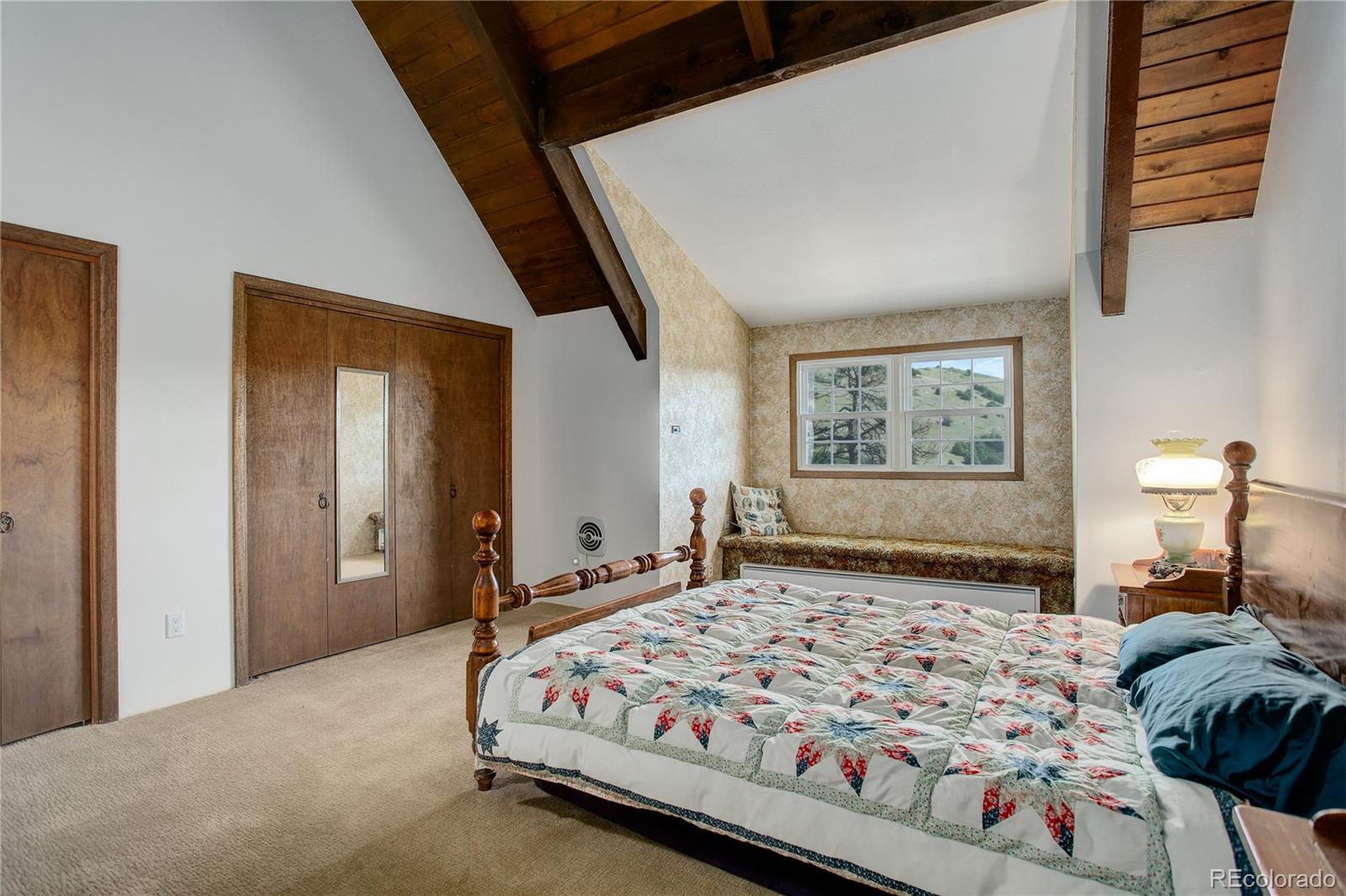 19285 Fox Den Way Morrison, CO 80465 - Photo 18 of 24 a bedroom with a large bed and a chandelier