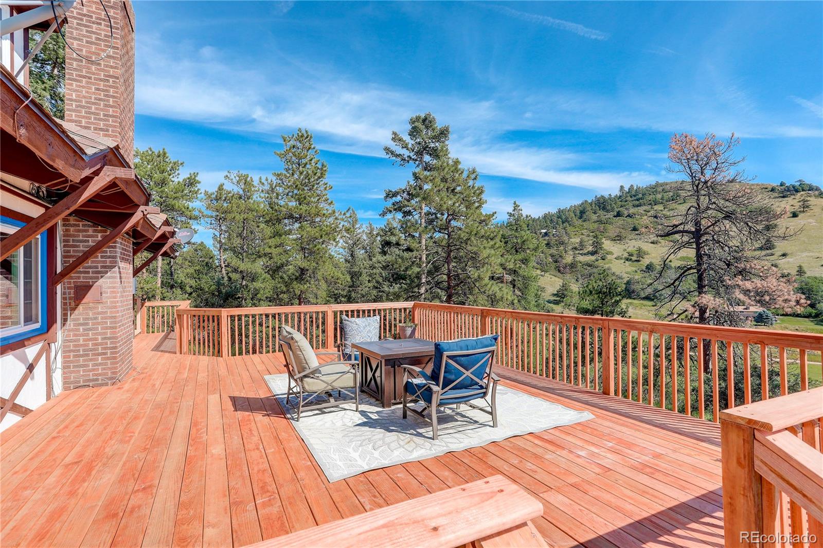 19285 Fox Den Way Morrison, CO 80465 - Photo 23 of 24 a view of a roof deck with table and chairs a barbeque with wooden floor and fence