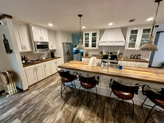 a living room with stainless steel appliances furniture a rug and a kitchen view