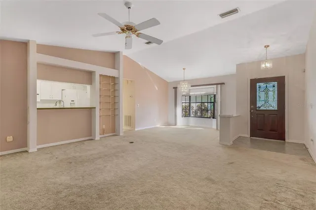 an empty room with chandelier fan and windows