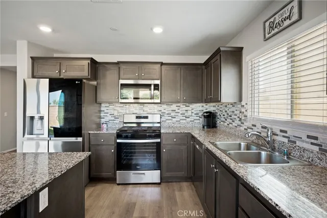 a kitchen with stainless steel appliances granite countertop a sink stove microwave and refrigerator