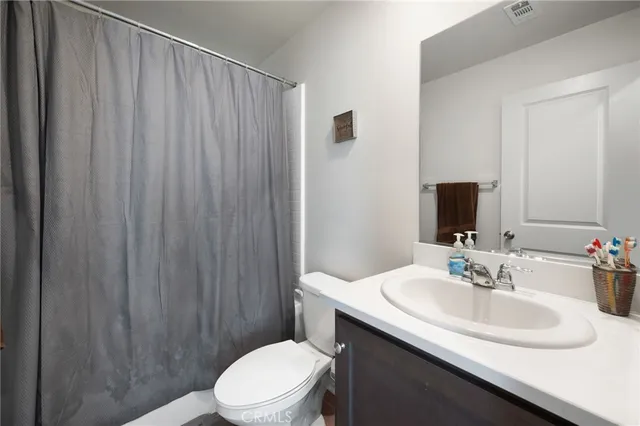 a bathroom with a sink a toilet a mirror and shower curtain