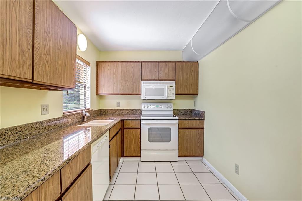 5501 Rattlesnake Hamm Road, Unit 109 Naples, FL 34113 - Photo 7 of 17 a kitchen with a stove top oven sink and cabinets
