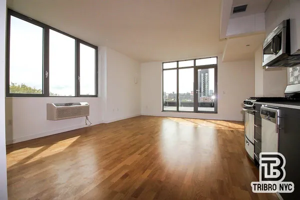 a view of an empty room with a window and wooden floor