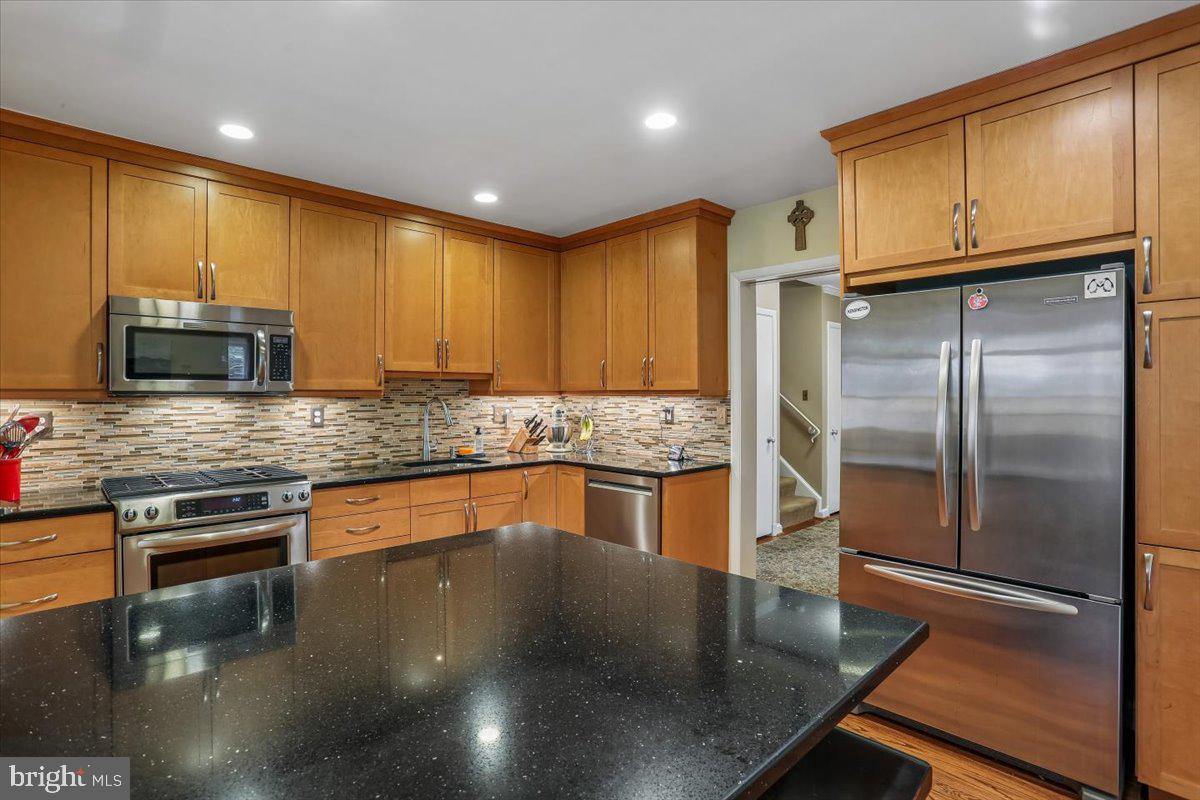 3612 Littledale Road Kensington, MD 20895 - Photo 22 of 79 a kitchen with stainless steel appliances granite countertop a refrigerator a stove and a sink with wooden cabinets