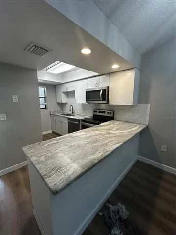 a kitchen with a sink a counter top space cabinets and stainless steel appliances