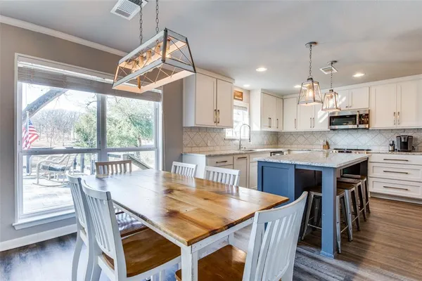 a kitchen with stainless steel appliances granite countertop a stove a refrigerator a kitchen island a table and chairs