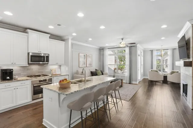 a kitchen with stainless steel appliances granite countertop a stove top oven a sink dishwasher a dining table and chairs with wooden floor