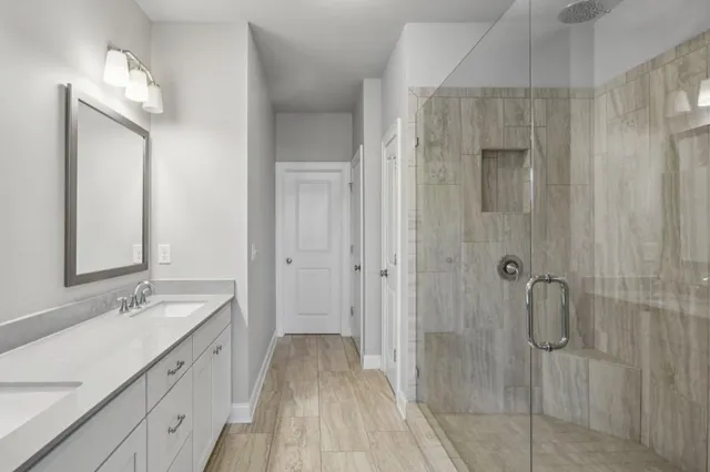a spacious bathroom with a double vanity sink a large mirror and shower