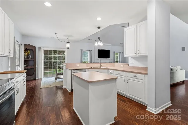 a kitchen with kitchen island granite countertop a sink appliances cabinets and wooden floor