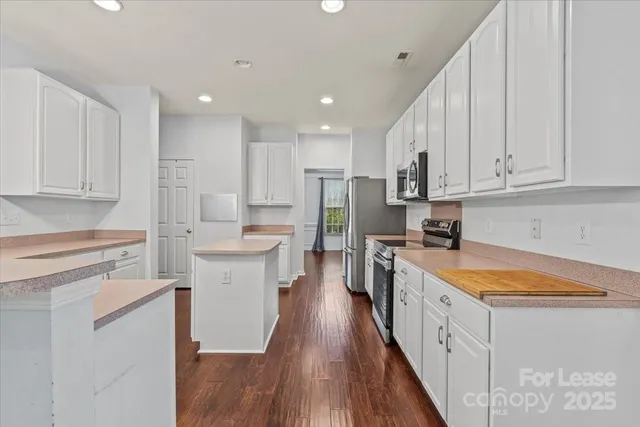 a kitchen with kitchen island granite countertop a sink a counter top space stainless steel appliances and cabinets