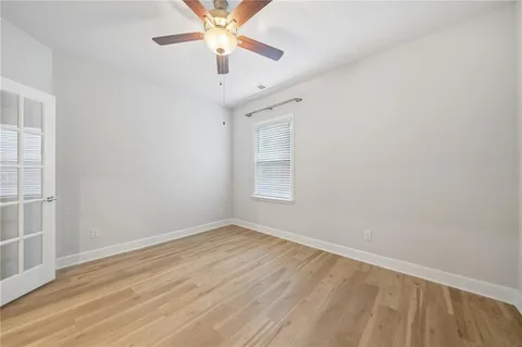 an empty room with wooden floor chandelier fan and windows
