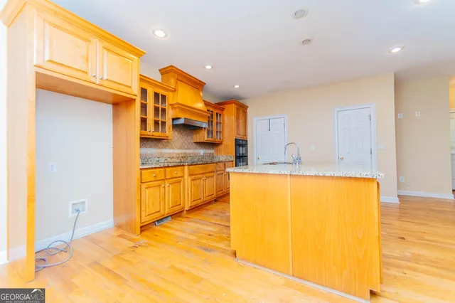 a view of kitchen with kitchen island a sink a stove and a refrigerator with wooden floor