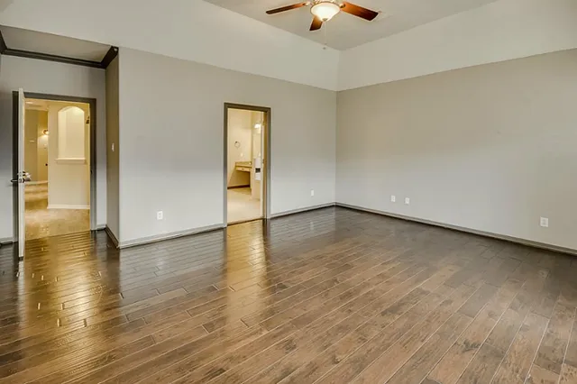 an empty room with wooden floor and windows with curtains view