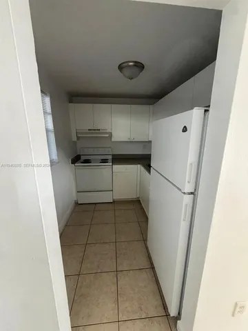 a kitchen with a refrigerator and white cabinets