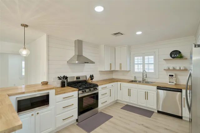 a kitchen with stainless steel appliances granite countertop a sink a stove and a refrigerator