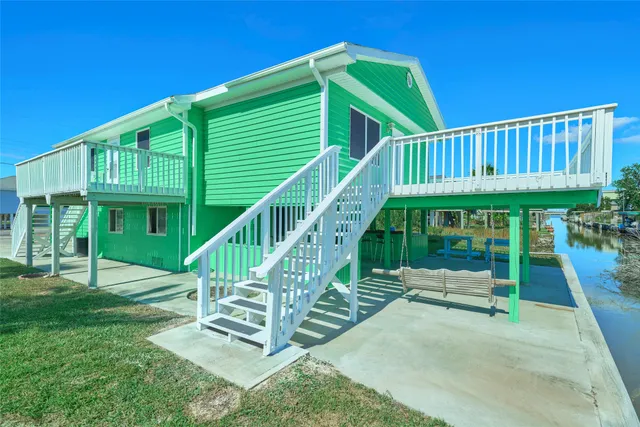 a view of house with a deck and a yard