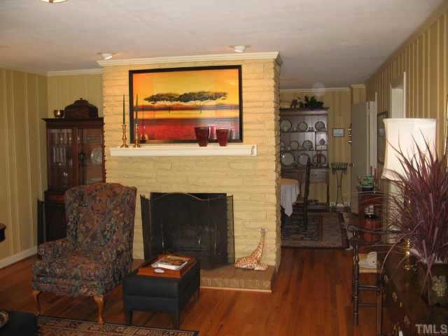 3046 Farrior Road Raleigh, NC 27607 - Photo 2 of 10 a living room with furniture a fireplace and a floor to ceiling window