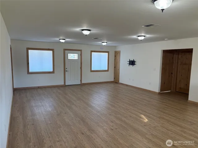an empty room with wooden floor and windows