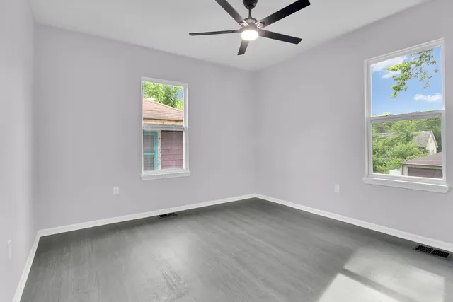 a view of an empty room with a window and wooden floor