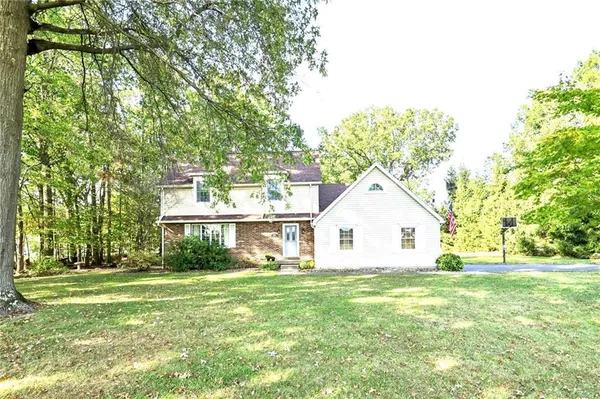a view of white house with a big yard and large trees